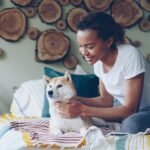 Cachorro sente quando alguém vai morrer: tutora fazendo carinho no cão deitado na cama