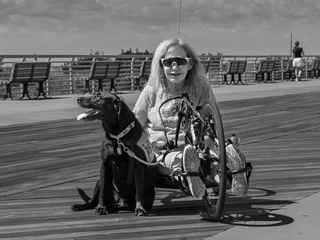 Cão de suporte emocional: mulher em handbike acompanhada do cão de serviço em um calçadão