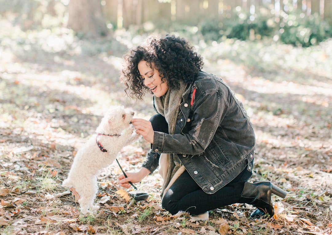 Nome de cachorro macho: tutora de jaqueta preta segurando um cão branco no colo