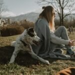 Mulher e cão relaxando juntos em um parque gramado