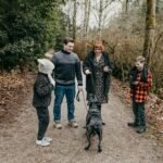 Benefícios de ter um cachorro em casa: família com duas crianças caminhando com o cão em trilha na floresta