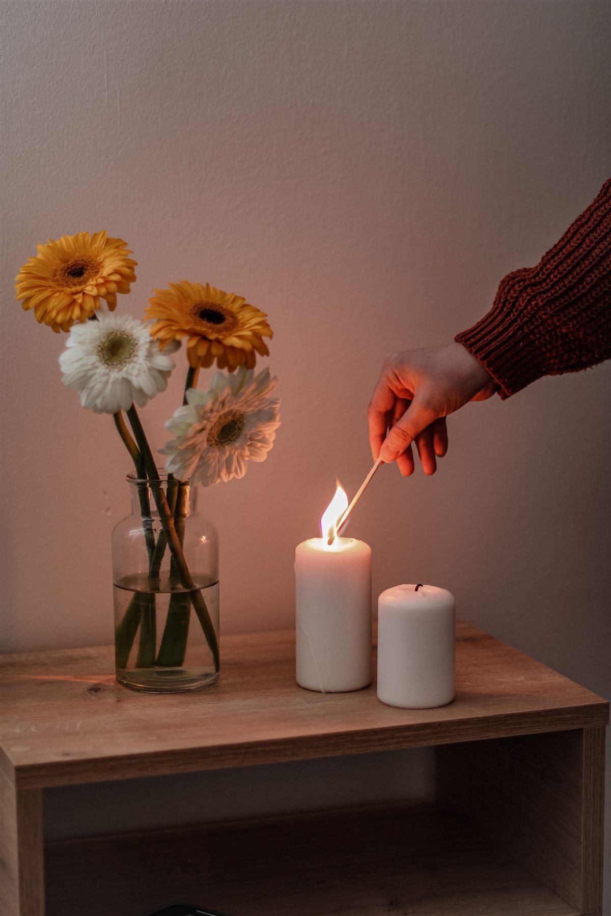 Cremação de cachorro: mão acendendo uma vela ao lado de um arranjo de flores