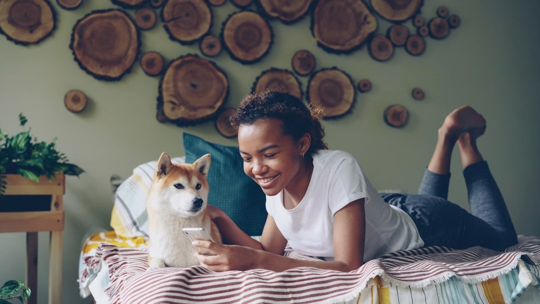 Dormir com o cachorro faz mal espiritualmente: tutora sorridente deitada na cama ao lado do cachorro em quarto aconchegante