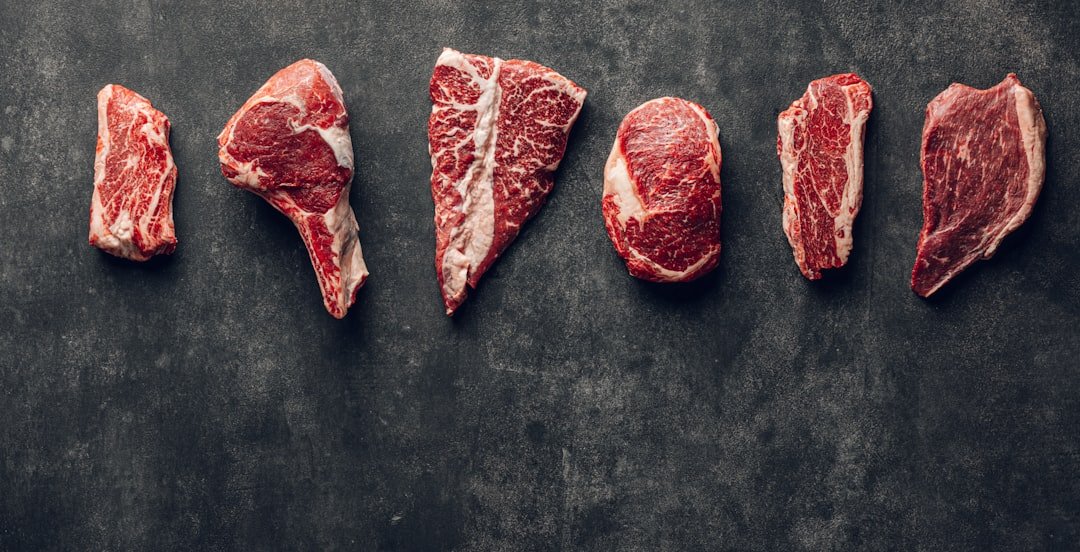Osso cozido para cachorro: diferentes cortes de carne crua com osso lado a lado sobre superfície escura
