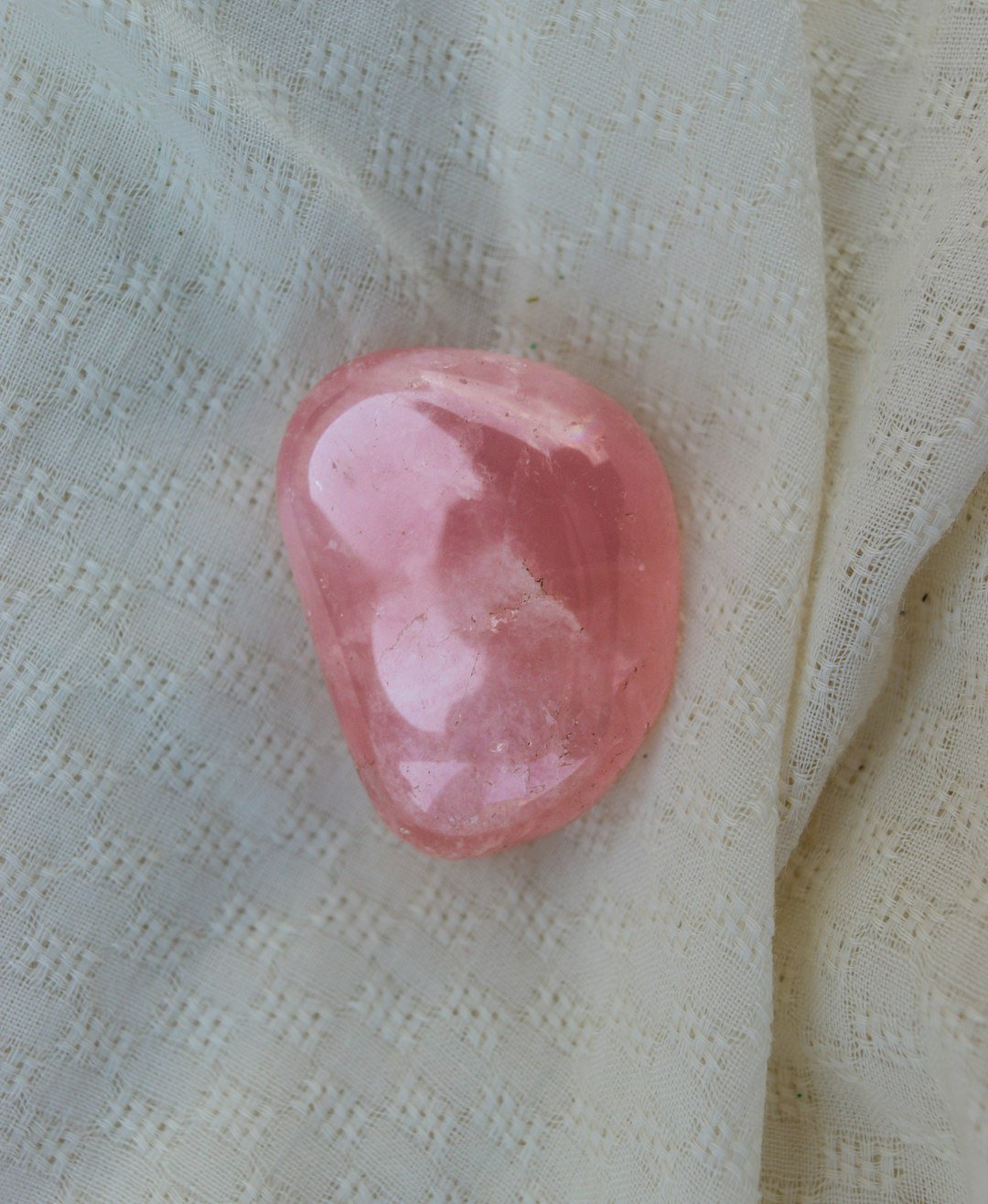 Cristais de proteção para cães: pedra de quartzo rosa lapidada sobre tecido claro