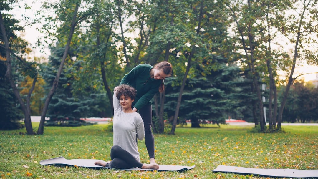 Doga: instrutora auxiliando aluna em postura de yoga ao ar livre no parque