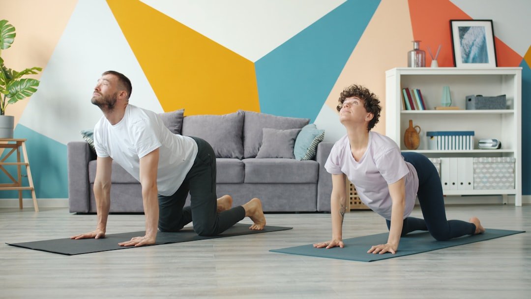 Doga: casal praticando a postura de yoga gato-vaca lado a lado em casa