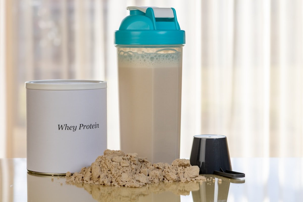 Proteínas para cachorros: pote de whey protein ao lado de uma coqueteleira e um medidor com o pó